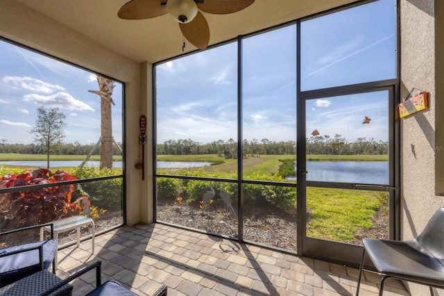 sunroom featuring a water view and ceiling fan