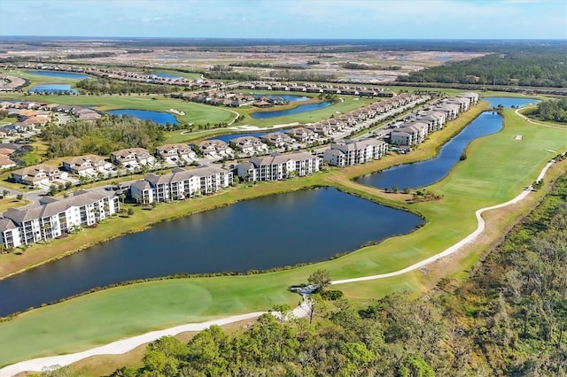 drone / aerial view of a local golf course, a nearby body of water, and apartment complex / building
