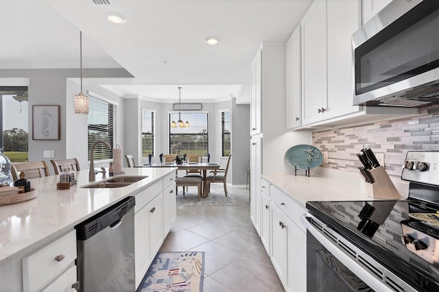 kitchen featuring appliances with stainless steel finishes, a sink, backsplash, crown molding, and light stone countertops