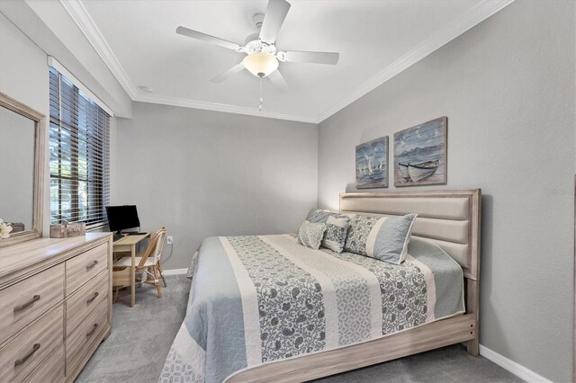 bedroom featuring light carpet, baseboards, a desk, ornamental molding, and ceiling fan
