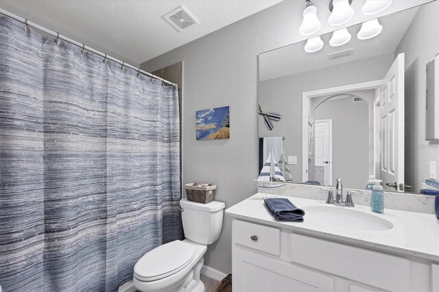 bathroom featuring toilet, vanity, a textured wall, and a shower with curtain