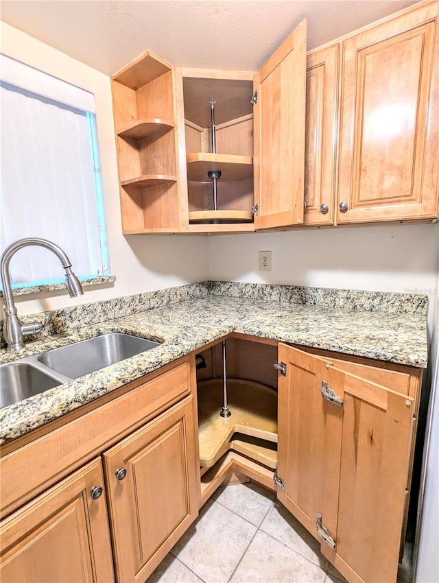 kitchen with light stone counters, sink, and light tile patterned flooring