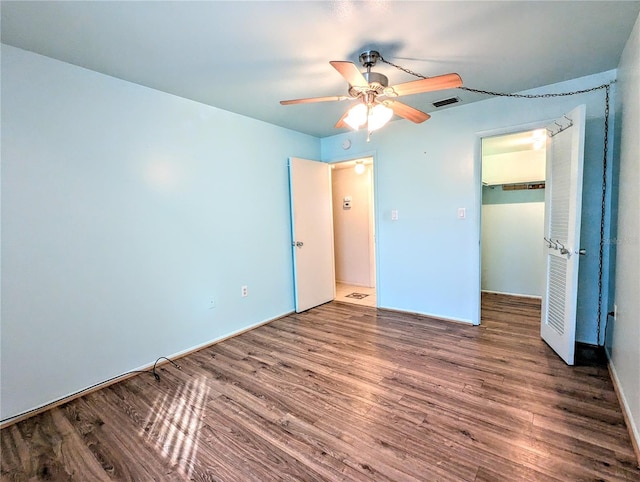 unfurnished bedroom with a closet, ceiling fan, dark hardwood / wood-style flooring, and a spacious closet