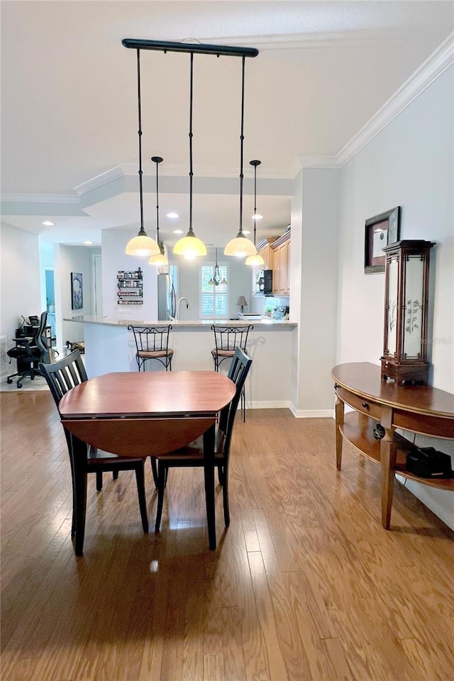 dining area featuring crown molding and light hardwood / wood-style flooring