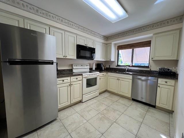 5171 Willow Links Unit 23, Sarasota, FL 34235 - kitchen featuring appliances with stainless steel finishes, light tile patterned floors, and dark stone countertops