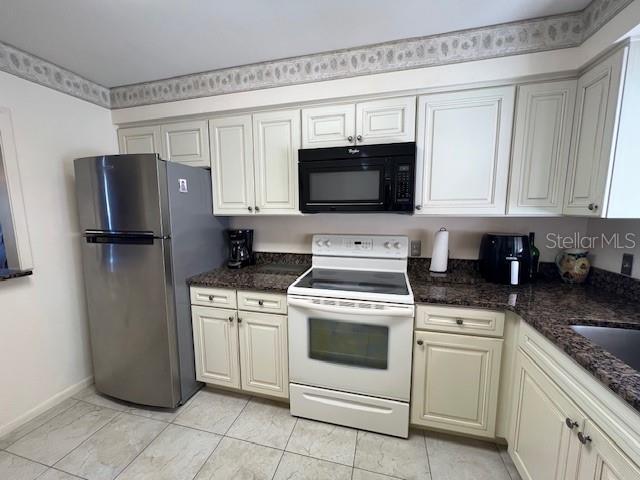 5171 Willow Links Unit 23, Sarasota, FL 34235 - kitchen with white electric range oven, freestanding refrigerator, black microwave, and dark stone countertops