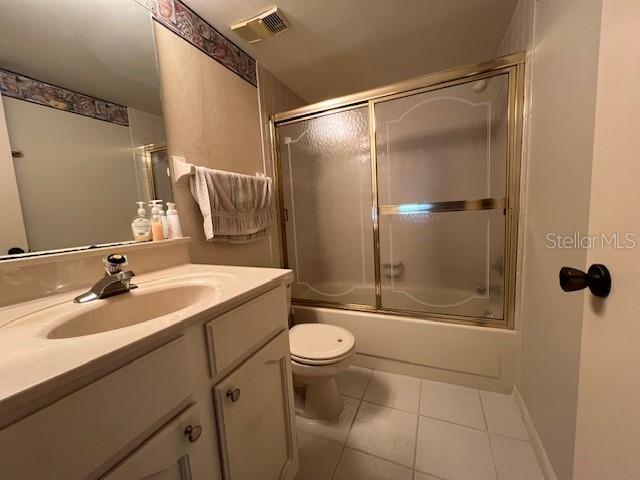 full bathroom featuring tile patterned flooring, vanity, toilet, and shower / bath combination with glass door