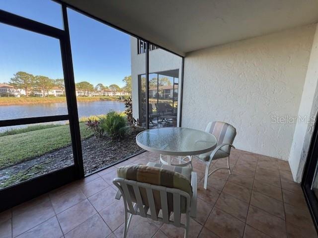 5171 Willow Links Unit 23, Sarasota, FL 34235 - sunroom with a textured wall, a water view, floor to ceiling windows, and tile patterned flooring
