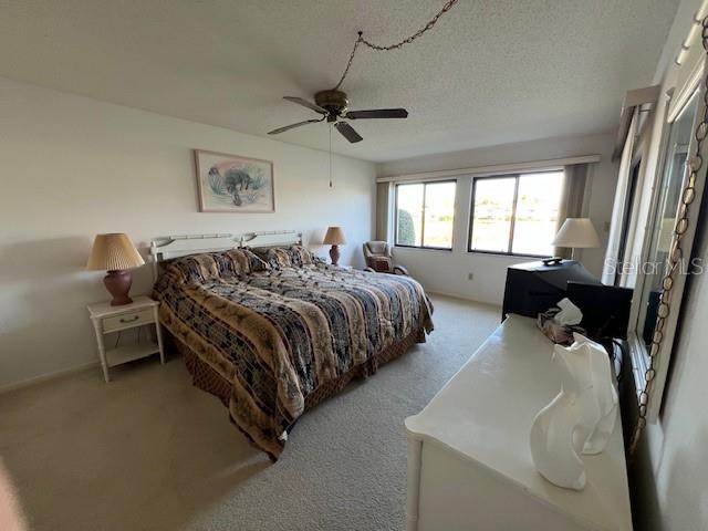 5171 Willow Links Unit 23, Sarasota, FL 34235 - bedroom with light colored carpet, ceiling fan, and a textured ceiling