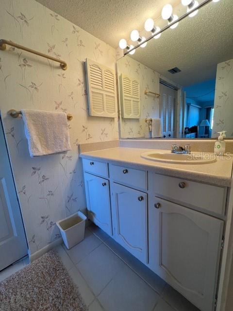 bathroom featuring tile patterned flooring, vanity, and a textured ceiling