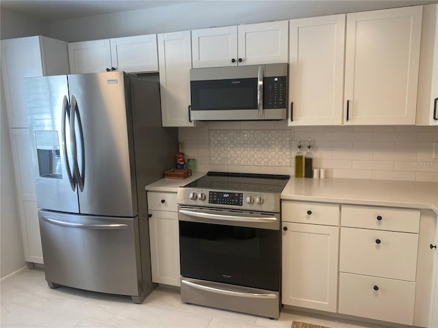 kitchen featuring stainless steel appliances, white cabinetry, and tasteful backsplash