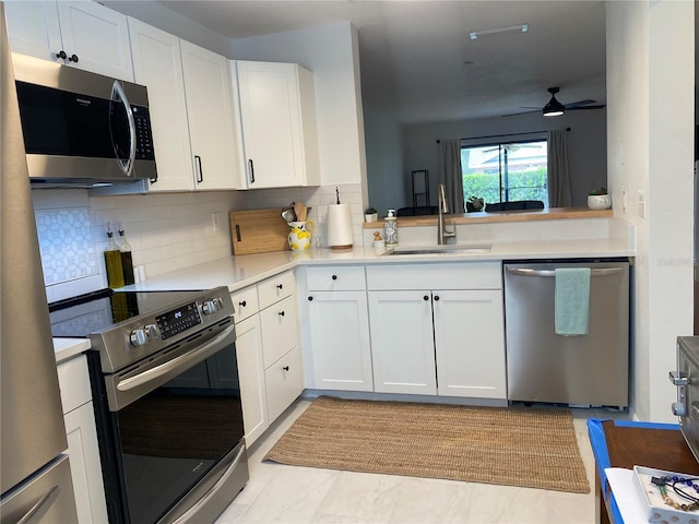 kitchen featuring white cabinetry, sink, ceiling fan, stainless steel appliances, and backsplash