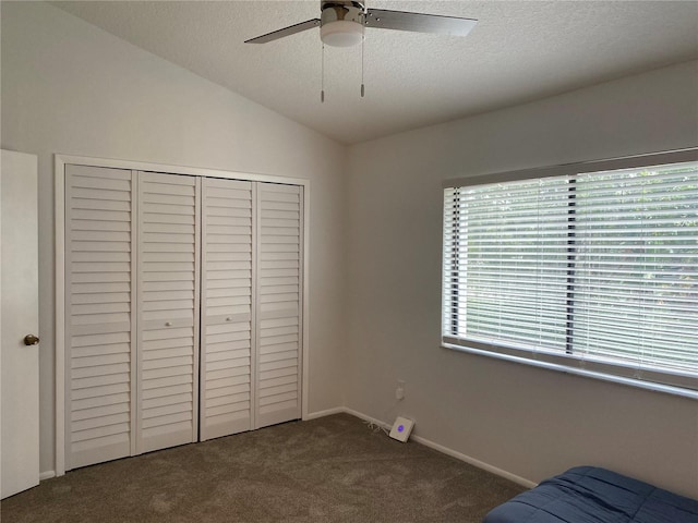 carpeted bedroom featuring ceiling fan, lofted ceiling, a textured ceiling, and a closet