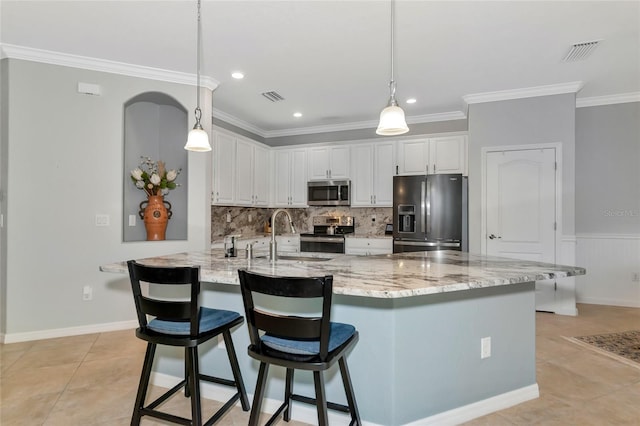 kitchen with appliances with stainless steel finishes, ornamental molding, sink, decorative light fixtures, and white cabinets