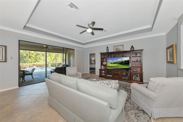 tiled living room featuring a raised ceiling, ceiling fan, and ornamental molding