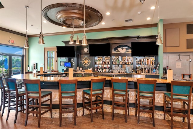 bar with decorative light fixtures, crown molding, dark wood-type flooring, and french doors