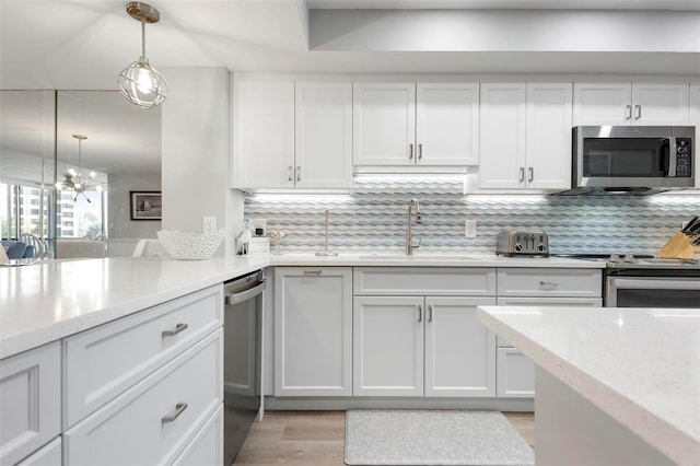 kitchen featuring stainless steel appliances, sink, pendant lighting, light hardwood / wood-style flooring, and white cabinetry