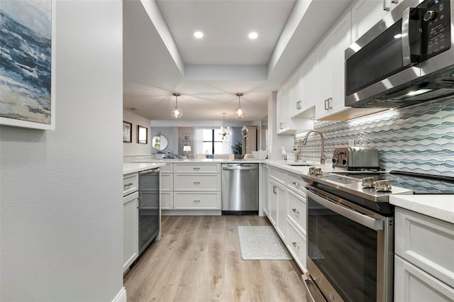 kitchen with sink, stainless steel appliances, backsplash, kitchen peninsula, and white cabinets