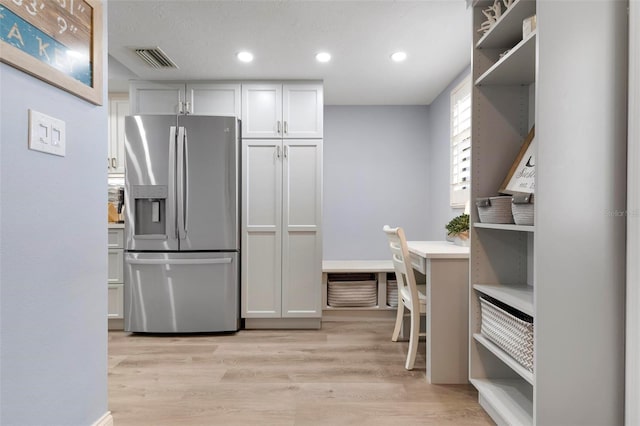 kitchen with white cabinets, light hardwood / wood-style floors, and stainless steel refrigerator with ice dispenser