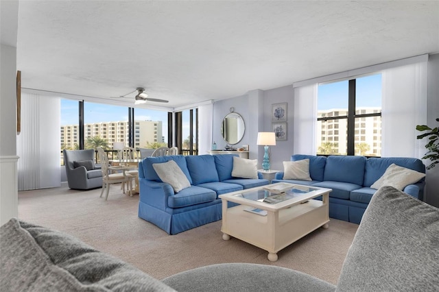 carpeted living room with a textured ceiling, expansive windows, ceiling fan, and a healthy amount of sunlight