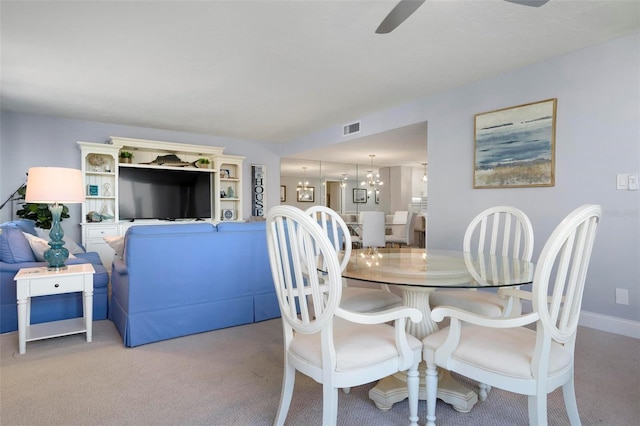 dining space with light carpet and ceiling fan with notable chandelier