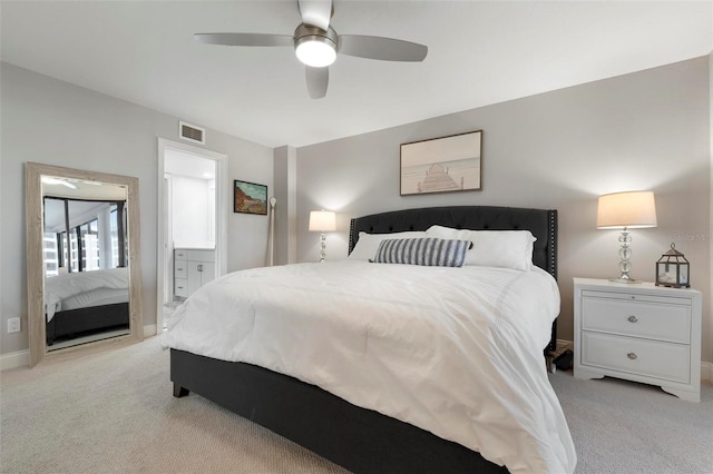 bedroom featuring ceiling fan, ensuite bathroom, and light colored carpet