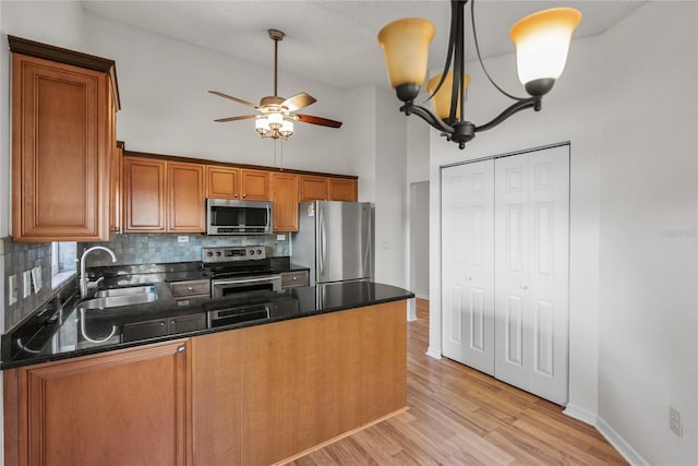 kitchen featuring pendant lighting, backsplash, sink, light hardwood / wood-style floors, and stainless steel appliances