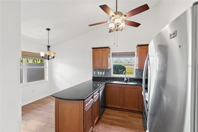 kitchen featuring sink, wood-type flooring, decorative light fixtures, decorative backsplash, and appliances with stainless steel finishes