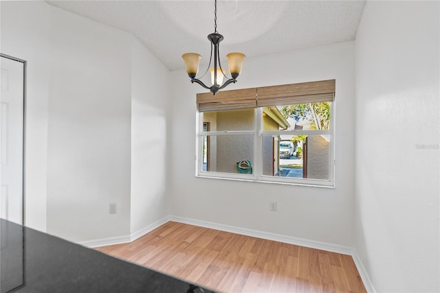 unfurnished room with hardwood / wood-style flooring, a textured ceiling, and an inviting chandelier