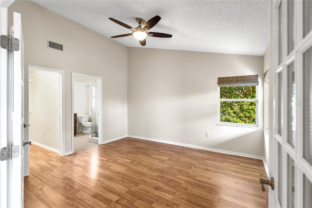 empty room featuring ceiling fan, high vaulted ceiling, a textured ceiling, and light wood-type flooring