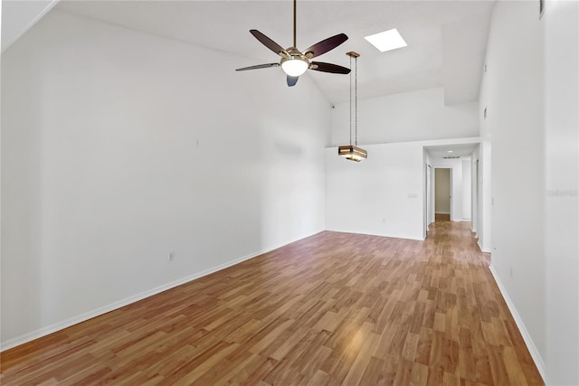 unfurnished living room with light wood-type flooring, a skylight, high vaulted ceiling, and ceiling fan