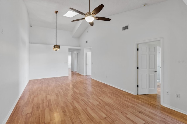 unfurnished living room featuring light wood-type flooring, a skylight, high vaulted ceiling, and ceiling fan