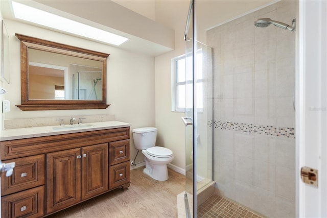 bathroom featuring tiled shower, toilet, vanity, and hardwood / wood-style flooring