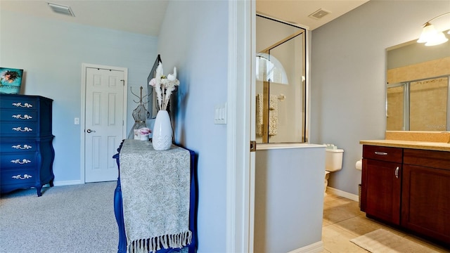 bathroom featuring tile patterned floors, toilet, vanity, and walk in shower