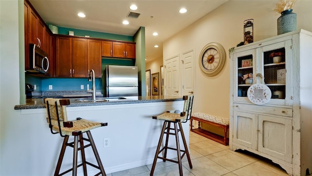 4046 Overture Cir Unit 4046, Bradenton, FL 34209 - kitchen with stainless steel appliances, a peninsula, a kitchen bar, light tile patterned floors, and recessed lighting
