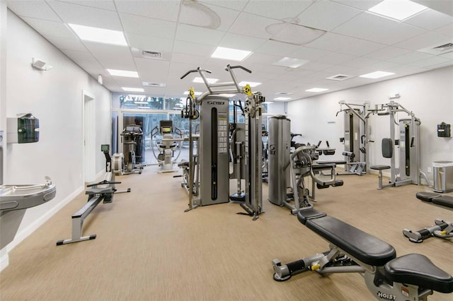 exercise room featuring a drop ceiling and light colored carpet