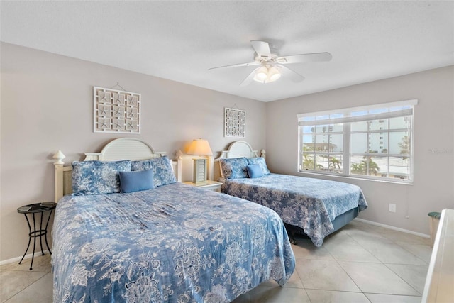 bedroom featuring ceiling fan, light tile patterned floors, and a textured ceiling