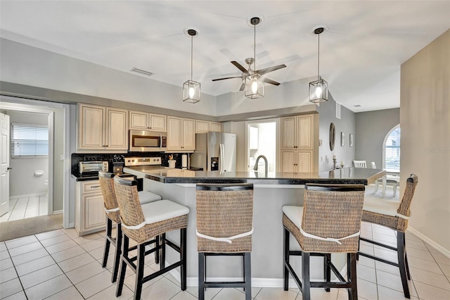 kitchen featuring a wealth of natural light, light tile patterned flooring, a kitchen bar, and appliances with stainless steel finishes