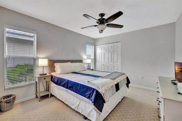 carpeted bedroom featuring multiple windows, ceiling fan, and a closet