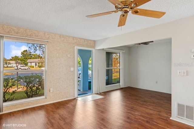 empty room with ceiling fan, wood-type flooring, a textured ceiling, and a wealth of natural light