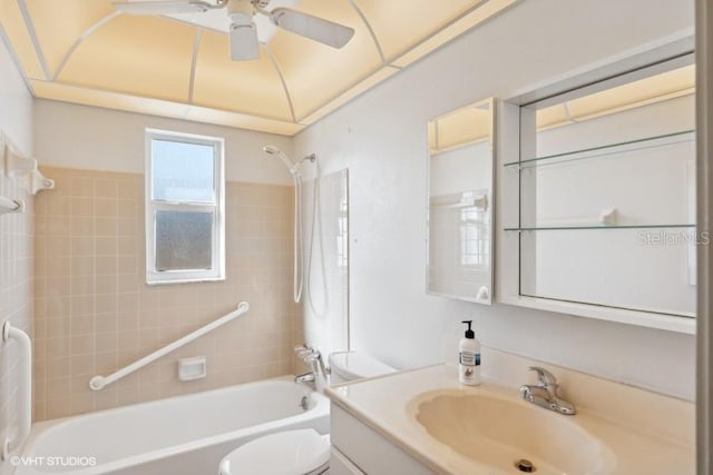 full bathroom featuring ceiling fan, vanity, tiled shower / bath combo, and toilet