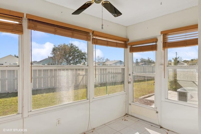 unfurnished sunroom featuring ceiling fan and a healthy amount of sunlight