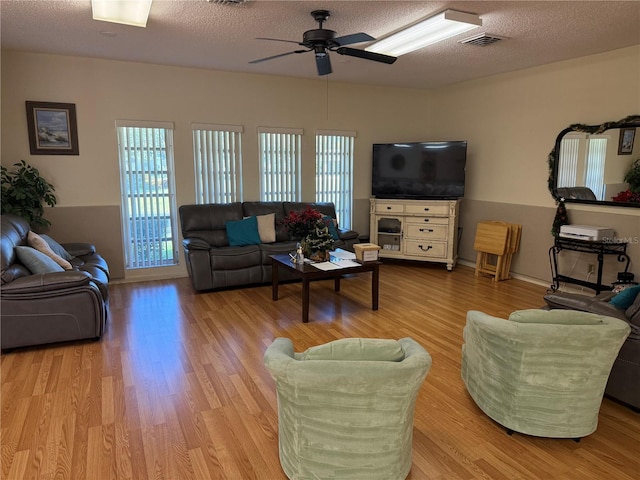 living room featuring plenty of natural light, light hardwood / wood-style floors, a textured ceiling, and ceiling fan