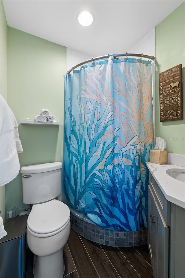 bathroom with a shower with shower curtain, hardwood / wood-style floors, vanity, and toilet