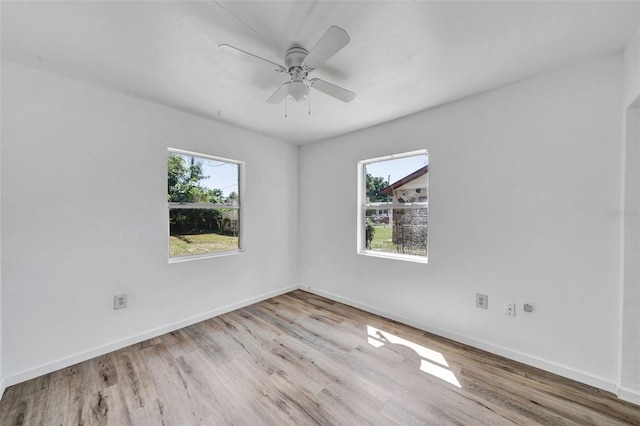 unfurnished room featuring a wealth of natural light, ceiling fan, and light wood-type flooring