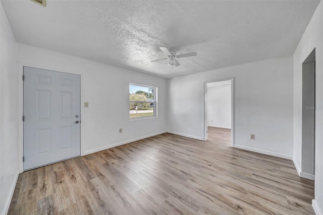 spare room with ceiling fan, light wood-type flooring, and a textured ceiling