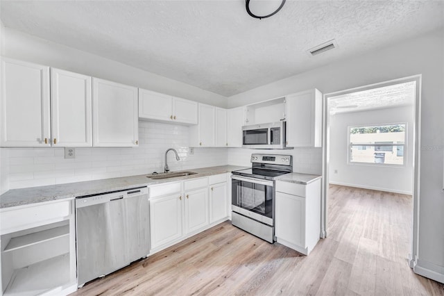 kitchen featuring white cabinetry, sink, stainless steel appliances, light hardwood / wood-style flooring, and a textured ceiling