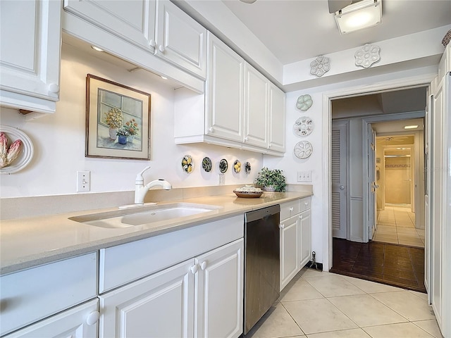 kitchen featuring white cabinetry, sink, light tile patterned flooring, and stainless steel dishwasher