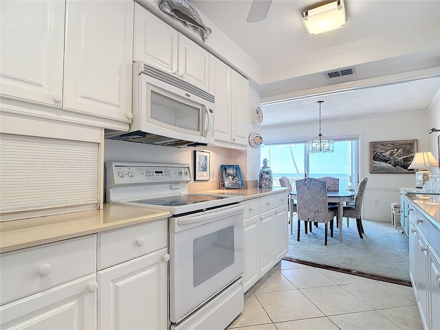 kitchen featuring white appliances, ceiling fan with notable chandelier, light tile patterned floors, white cabinets, and hanging light fixtures