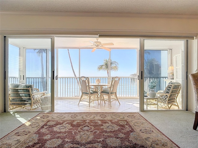 sunroom with a water view and ceiling fan